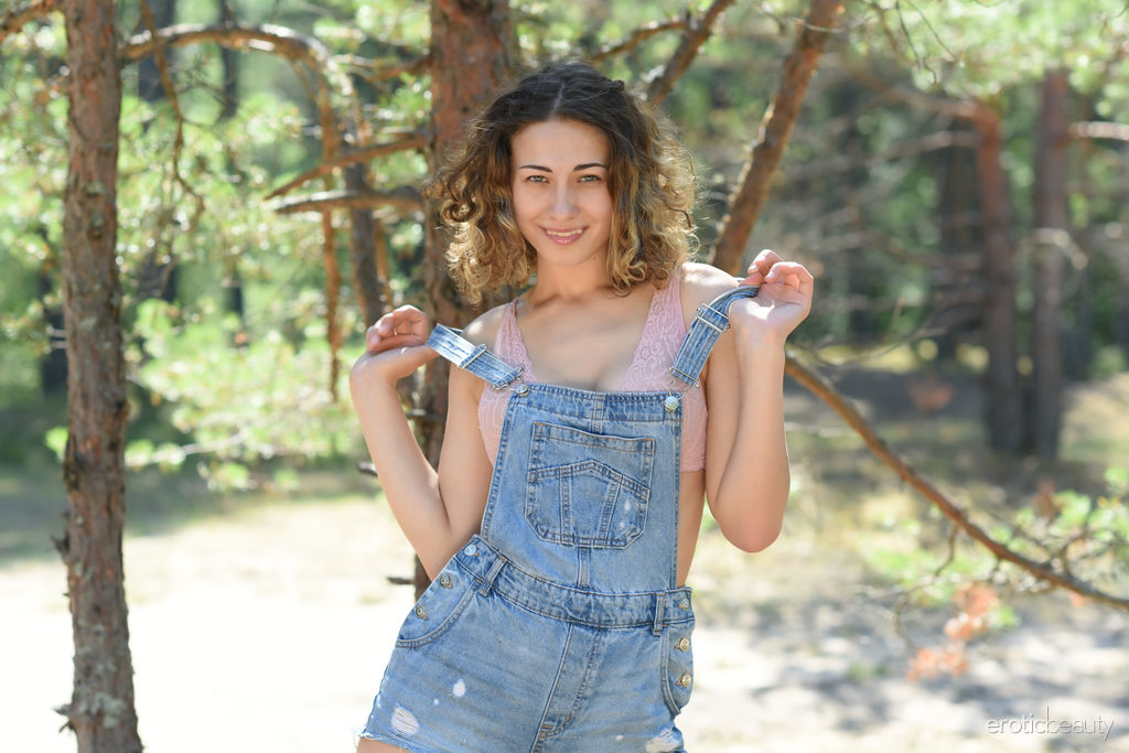 Ari  takes off her overalls in the woods and